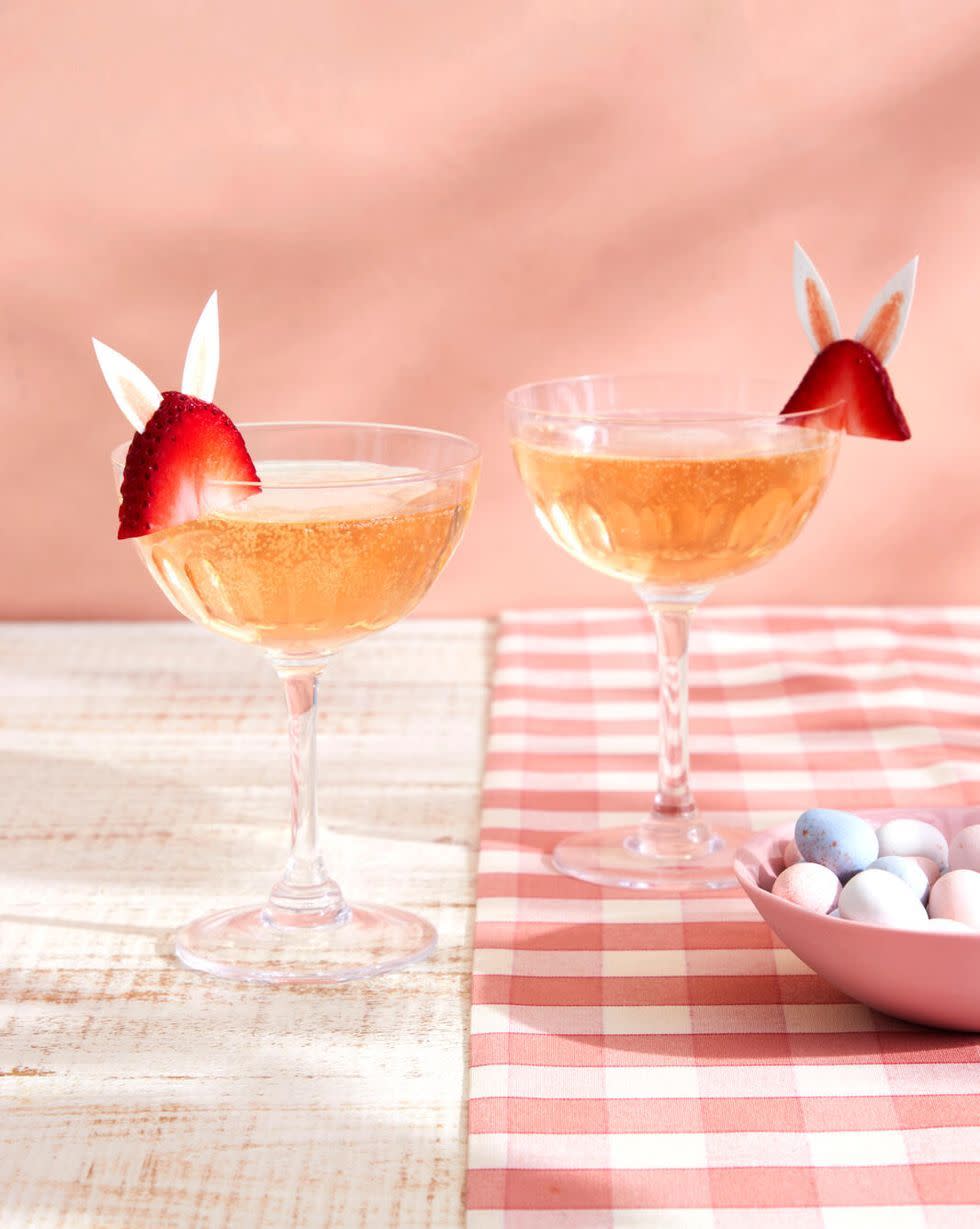 two glasses of liquid with straws and a bowl of fruit