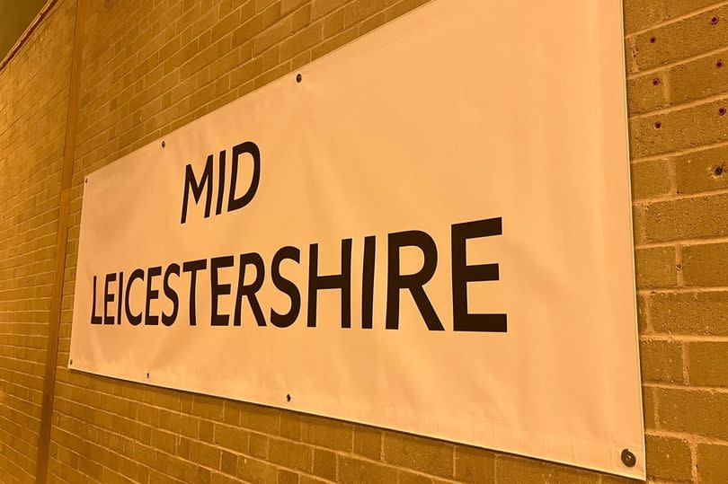 A sign on a brick wall says "Mid Leicestershire"