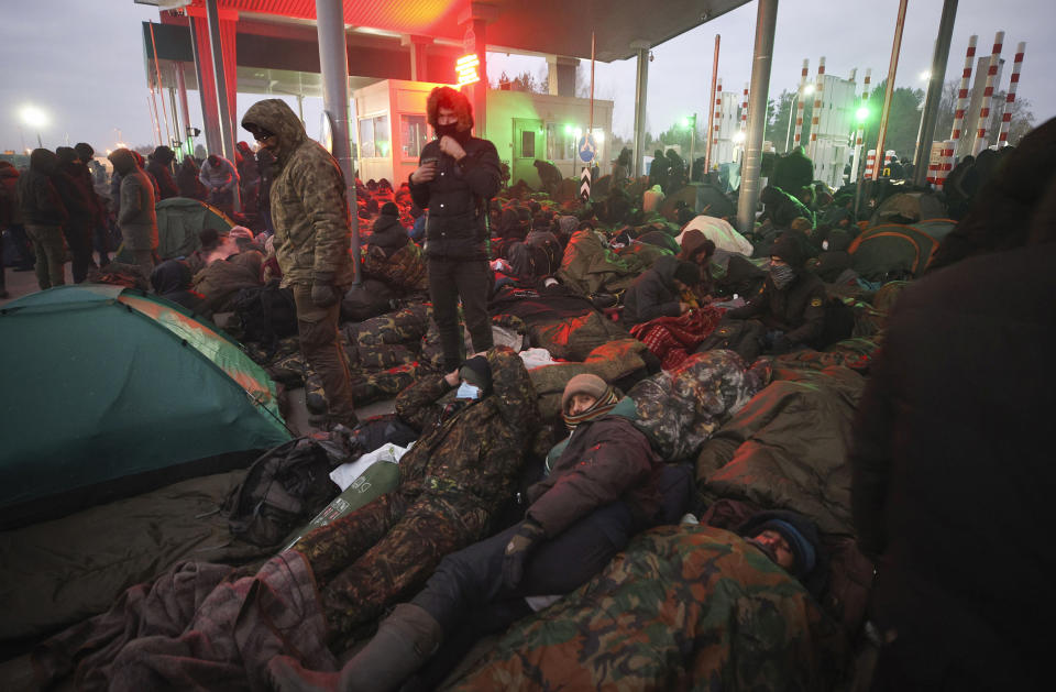 Migrants from the Middle East and elsewhere gather at the checkpoint "Kuznitsa" at the Belarus-Poland border near Grodno, Belarus, on Monday, Nov. 15, 2021. The EU is calling for humanitarian aid as up to 4,000 migrants are stuck in makeshift camps in freezing weather in Belarus while Poland has reinforced its border with 15,000 soldiers, in addition to border guards and police. (Leonid Shcheglov/BelTA via AP)