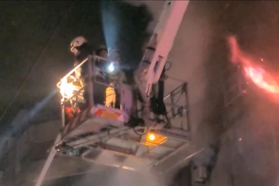 Firefighters on a crane tackle the blaze (AP)