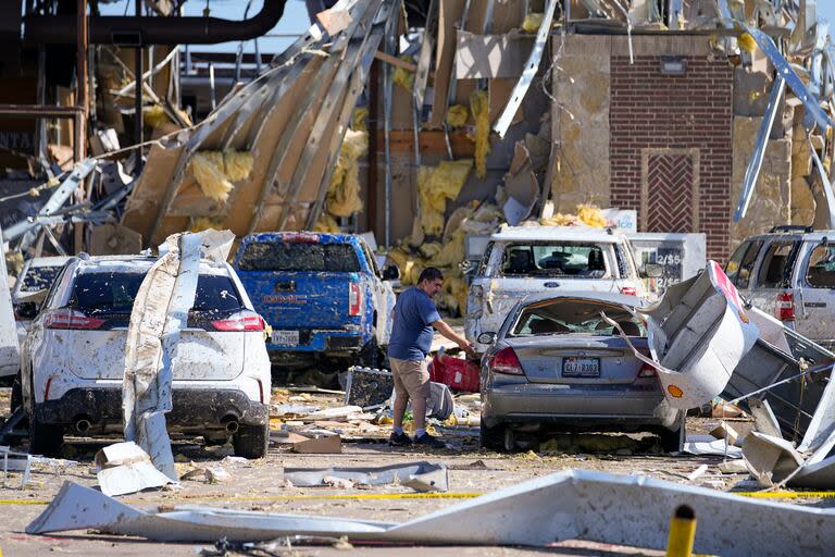 Un hombre mira a un auto dañado después de que un tornado pasara el día anterior.