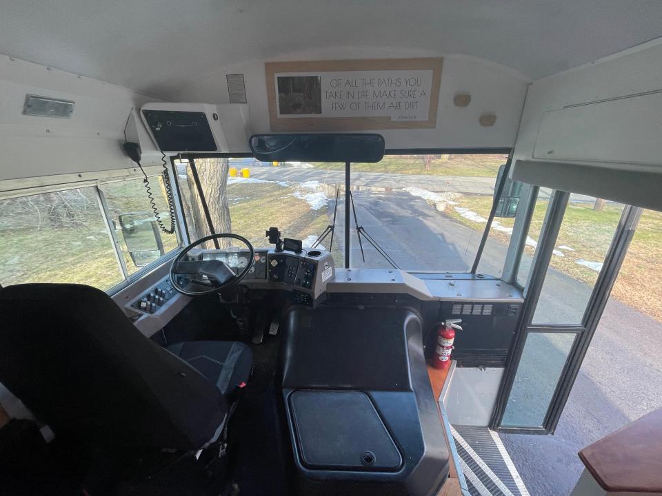 Front area of bus with doors open, black driver's seat, and black steering wheel