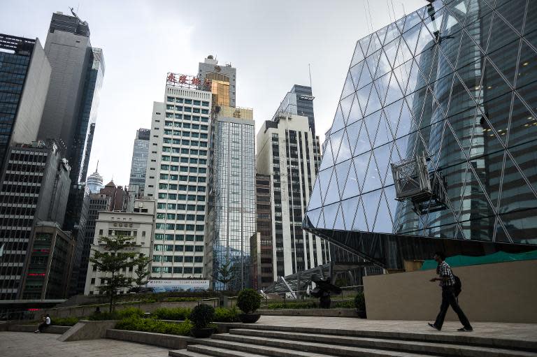 A man walks past high rise buildings in the central district of Hong Kong on July 9, 2014 where pro-democracy group Occupy Central has said it will stage a mass sit-in later this year