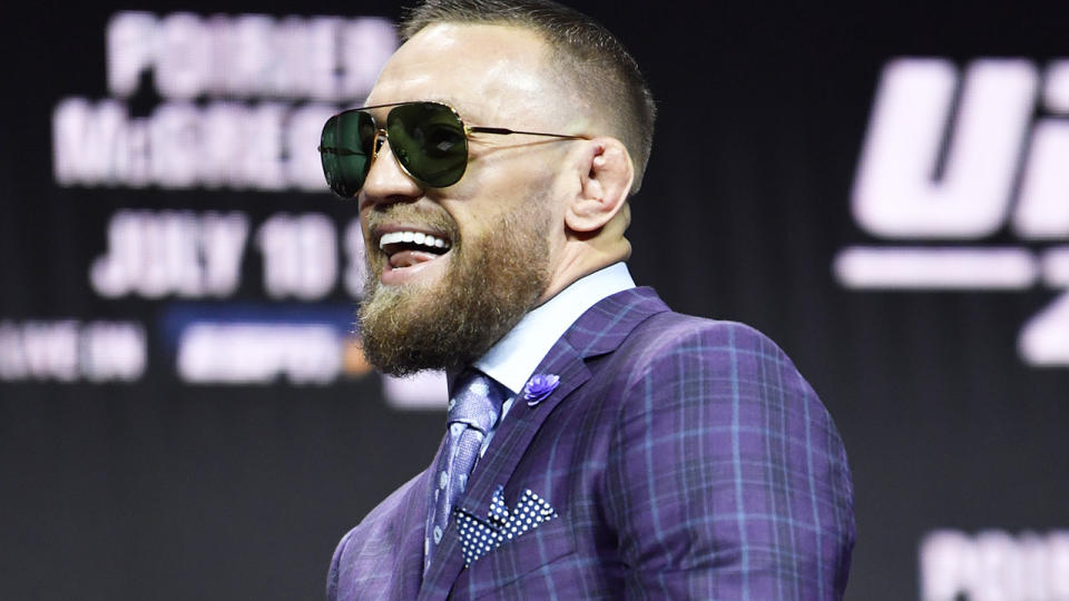 Conor McGregor grins as he walks out for his press conference ahead of UFC 264.