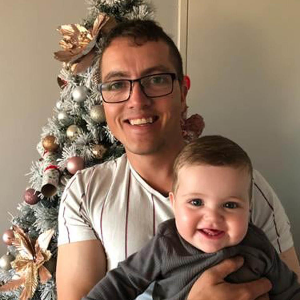 Aaron Stranney pictured with his son Faolan standing in front of a Christmas tree.