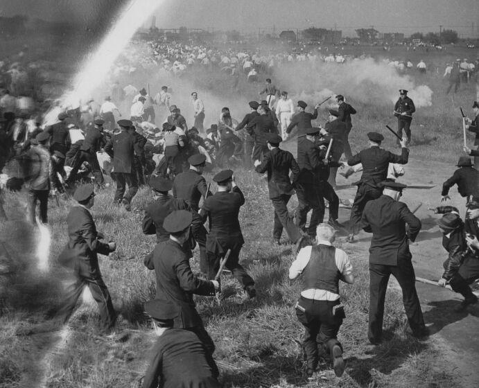 A black-and-white frame of a crowd of police officers confronting strikers - beating them with clubs