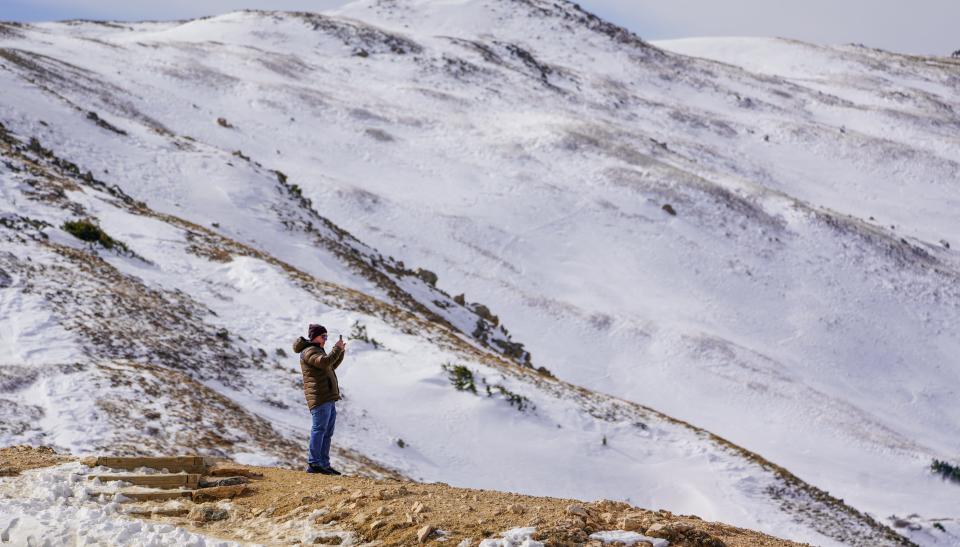 A tourist takes photo of snow on the Continental Divide atop Colorado's Loveland Pass in Silverthorne, Colorado on November, 6, 2023.