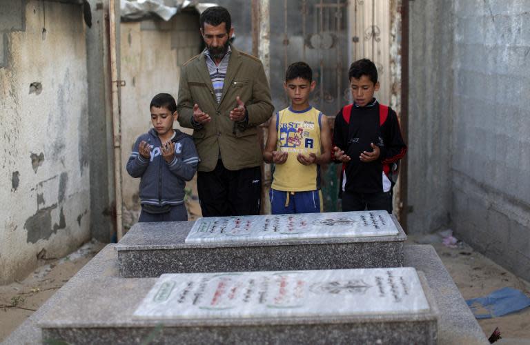 A Palestinian family visits the graves of relatives killed in an Israeli military strike on a beach in Gaza City during the 50-day war between Israel and Hamas militants in 2014