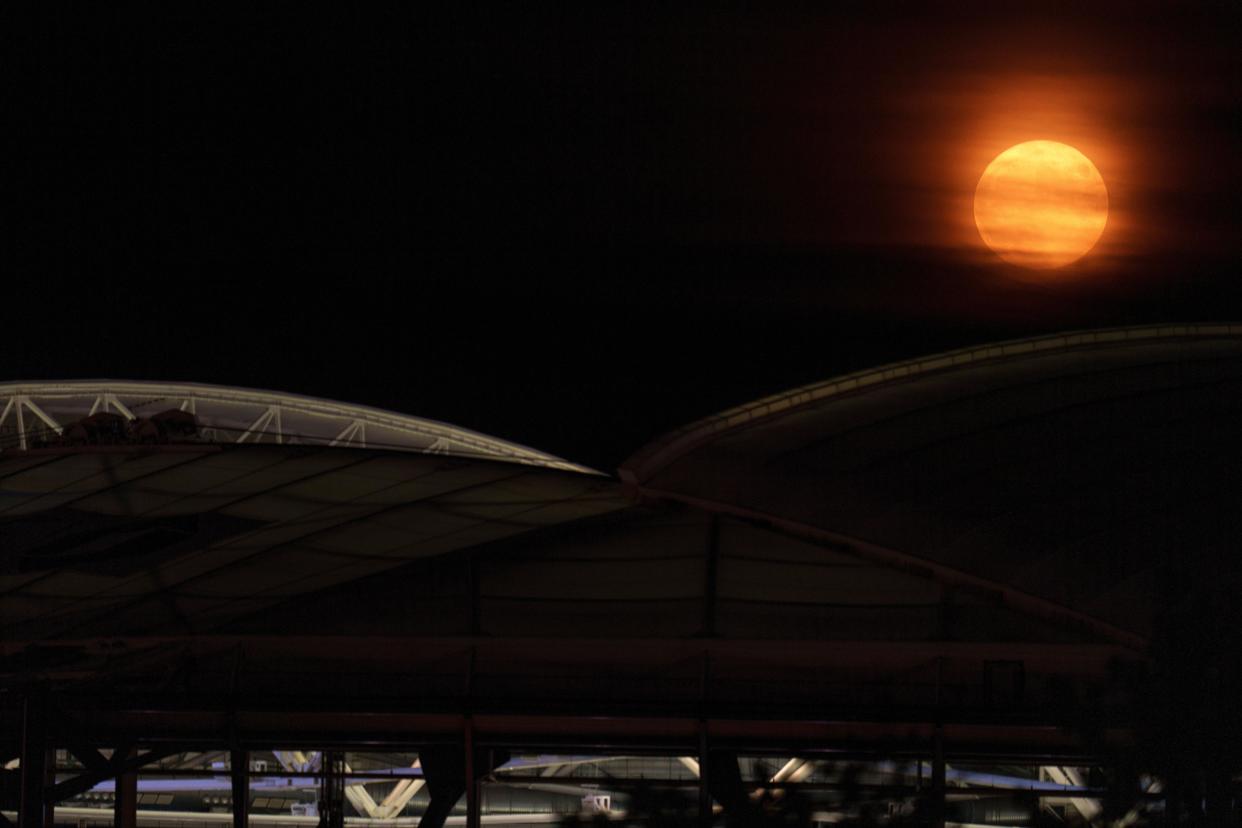 A super moon rises behind Arthur Ashe Stadium at the Billie Jean King National Tennis Center during the second round of the U.S. Open tennis championships, Wednesday, Aug. 30, 2023, in New York. A rare blue supermoon — the closest full moon of the year — dazzled stargazers Wednesday night. It was the second full moon of August, thus the blue label. And it was unusually close to Earth, therefore a supermoon. (AP Photo/Manu Fernandez)
