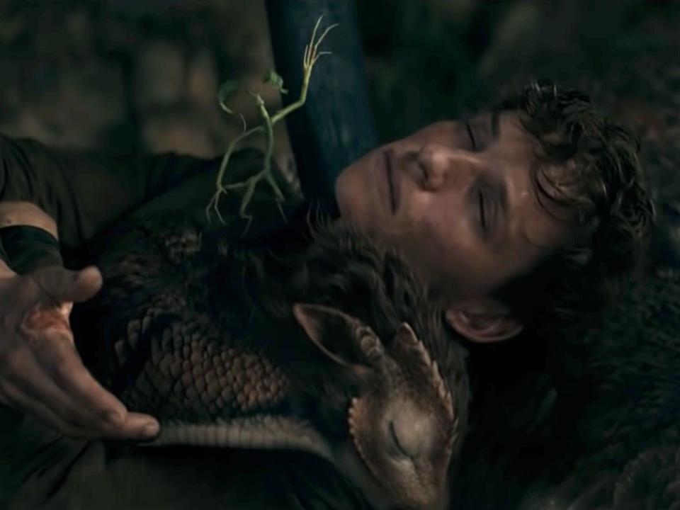 newt scamander (played by eddie redmayne) unconscious, clutching a small deer-like creature called the qilin