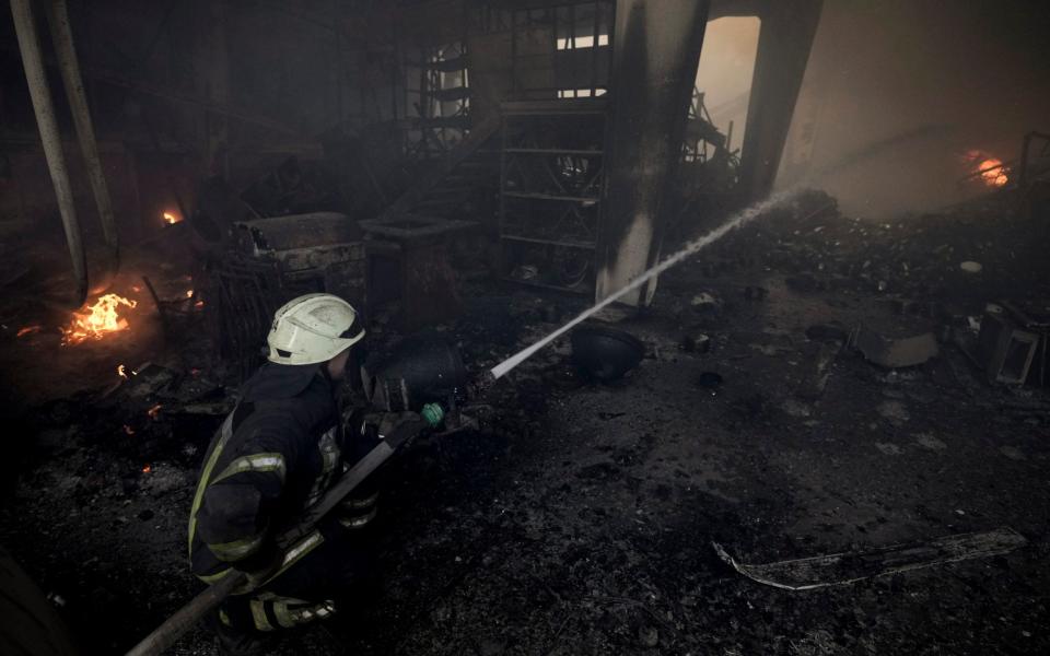 A Ukrainian firefighter sprays water inside a destroyed warehouse after a Russian bombardment on the outskirts of Kyiv, Ukraine - Vadim Ghirda/AP