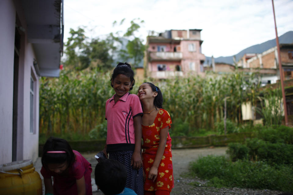 In this Tuesday, Aug. 21, 2012 photo, HIV patients Urmila Aryal, right, and Manju Chand share a light moment as they wait to wash dishes at the Saphalta HIV Shiksya Sadan School, in Kirtipur, near Katmandu. Over the past three years, ten orphan children with HIV have come to the two-story house converted into a school by a high-school teacher named Raj Kumar Pun and a friend just outside the capital of this Himalayan nation. Soon, though, the makeshift home and school will close, since Pun, who has become weighed down by the relentless bills of keeping everything running was forced to sell the house. (AP Photo/Niranjan Shrestha)