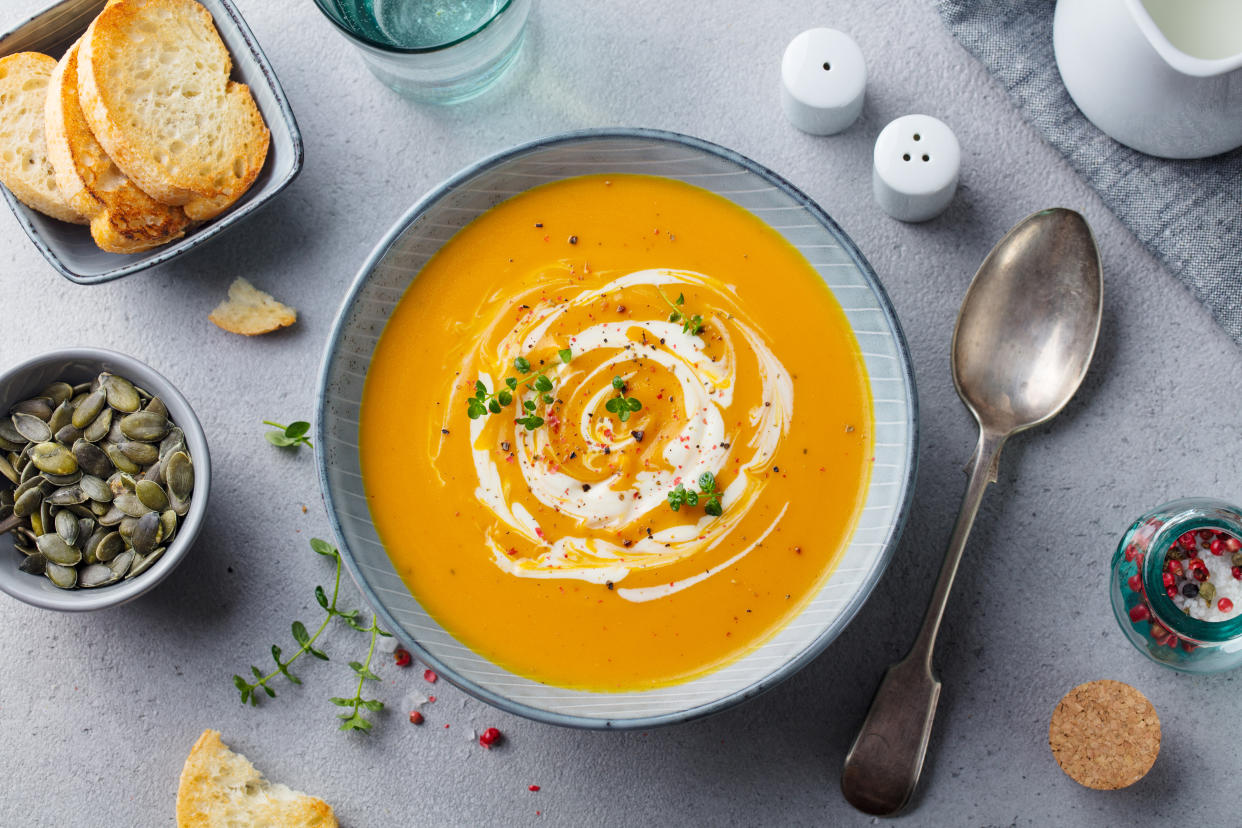 Pumpkin and carrot soup with cream on grey stone background. Top view UK heatwave