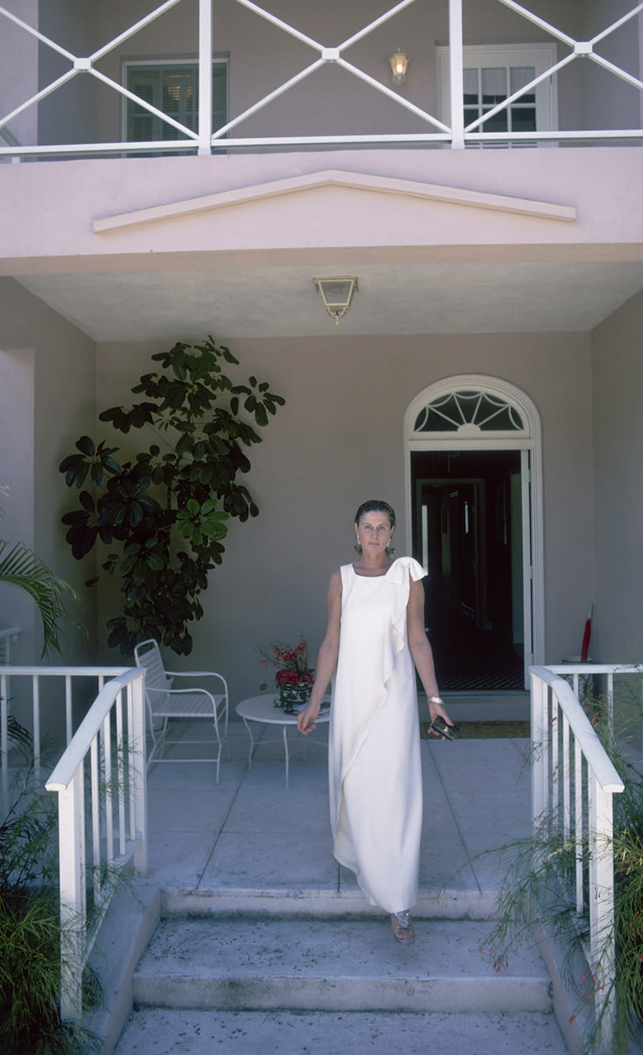 truman capote friends, swans, American socialite Nancy 'Slim' Keith, Lady Keith (1917 - 1990) steps onto her porch in Lyford Cay, New Providence Island, April 1974. (Photo by Slim Aarons/Hulton Archive/Getty Images)