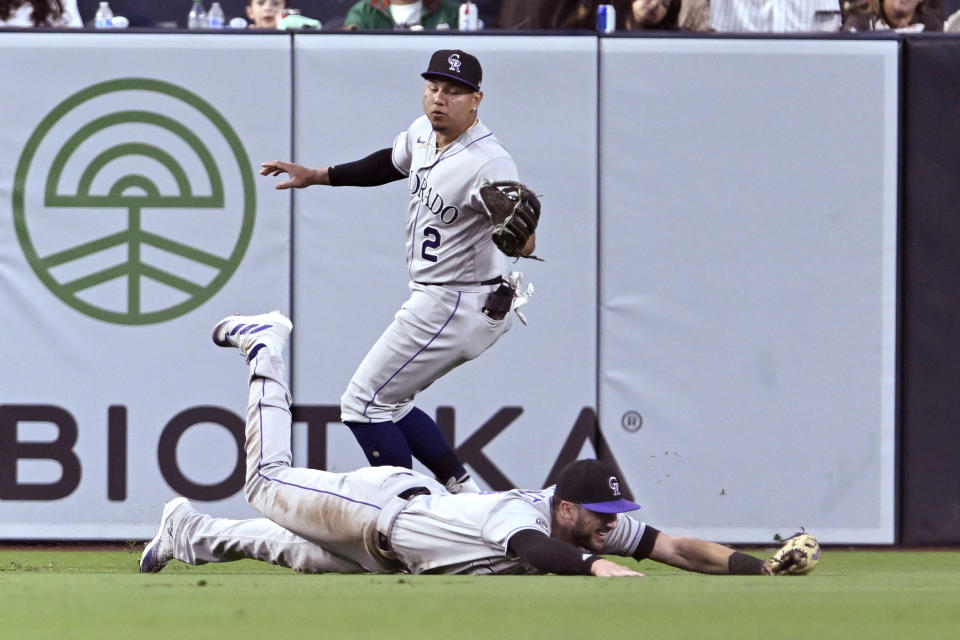 Colorado Rockies left fielder Kris Bryant slides while trapping the ball next to center fielder Yonathan Daza, on a single by San Diego Padres' Matt Carpenter during the fifth inning of a baseball game in San Diego, Saturday, April 1, 2023. (AP Photo/Alex Gallardo)