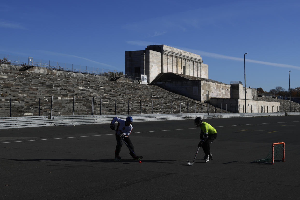 Young men play hockey in front of the main tribune at the 'Zeppelinfeld' of the 'Reichsparteigelande' (Nazi Party Rally Grounds) in Nuremberg, Germany, Wednesday, Nov. 18, 2020. Germany marks the 75th anniversary of the landmark Nuremberg trials of several Nazi leaders and in what is now seen as the birthplace of a new era of international law on Friday, Nov. 20, 2020. (AP Photo/Matthias Schrader)