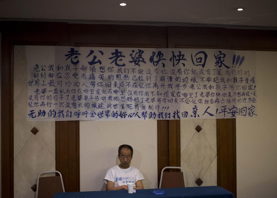 One of relatives of Chinese passengers on board the Malaysia Airlines Flight 370 sits underneath a banner written with messages dedicated to passengers of the missing plane during a briefing held by Malaysian officials at a hotel in Beijing, China Saturday, April 26, 2014. A number of Chinese relatives still aren't accepting the theory that the plane crashed in the Indian Ocean. They're insisting that Malaysian officials haven't told them the truth. The letters, top, reads " Husbands and wives, come home soon. " (AP Photo/Andy Wong)