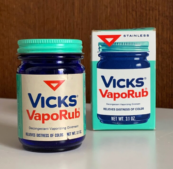 A jar of Vicks VapoRub and its box, showing the label "Decongestant Vaporizing Ointment. Relieves distress of colds. Net Wt. 3.1 oz."