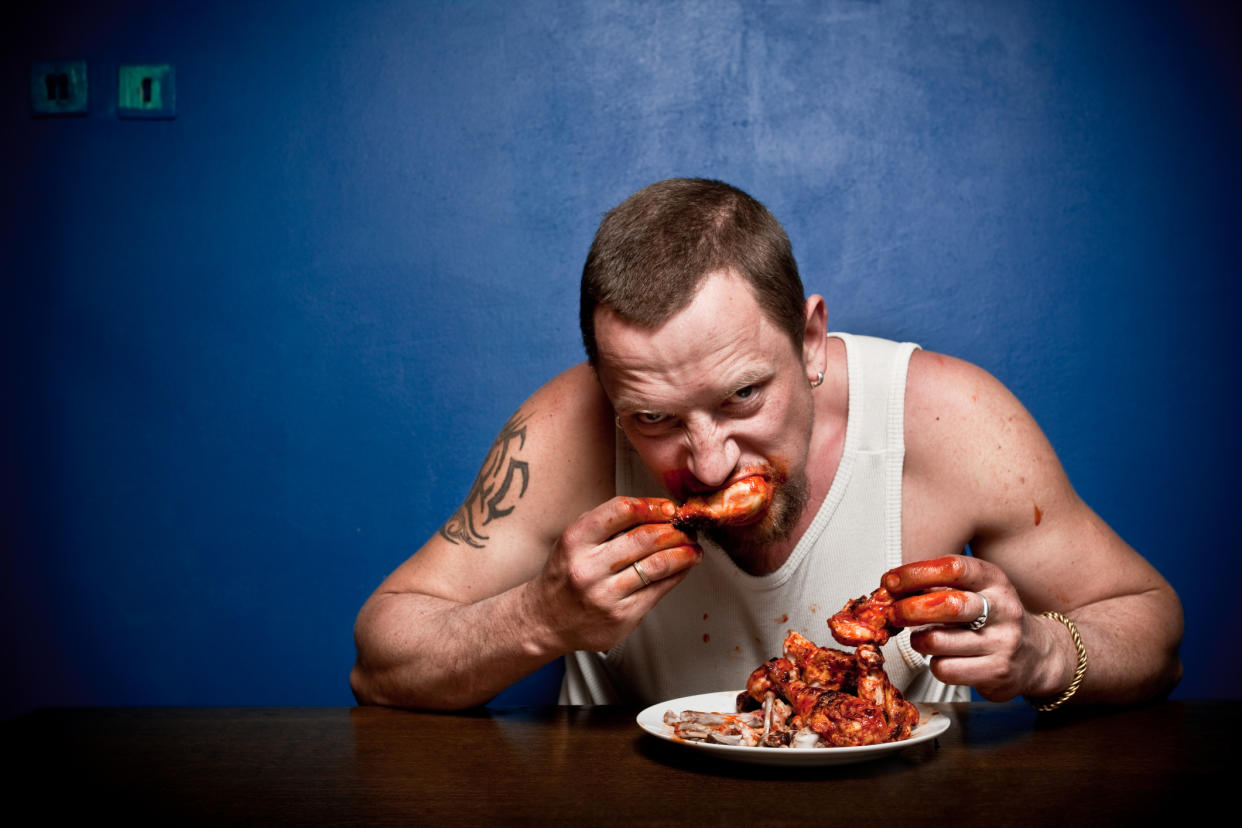 Big hungry man wildly eating grilled chicken and making big mess