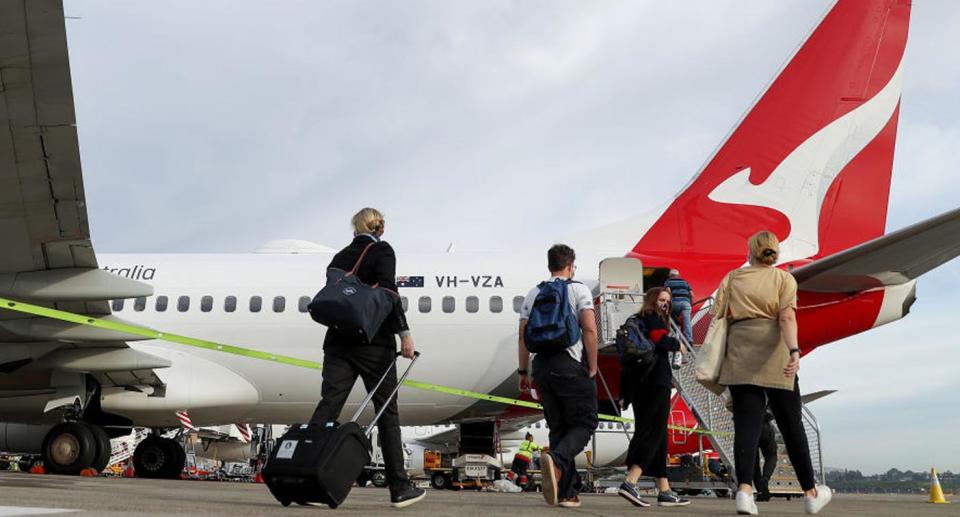 People walk to board Qantas plane.