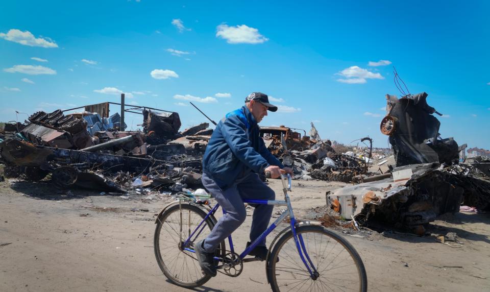 A resident rides a bike past a destroyed Russian military vehicle in Bucha, on the outskirts of Kyiv, Ukraine, on May 10, 2022.