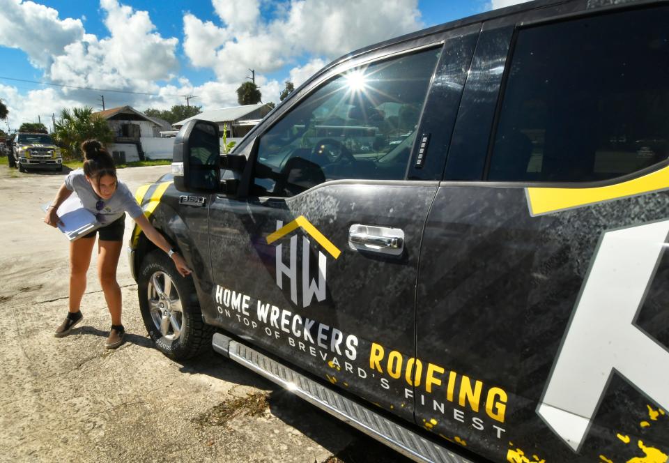 Brandi Lekander points at a Home Wreckers work truck that she said was swamped and ruined during Saturday's flood at the Avocado Avenue roofing-remodeling business in Eau Gallie.