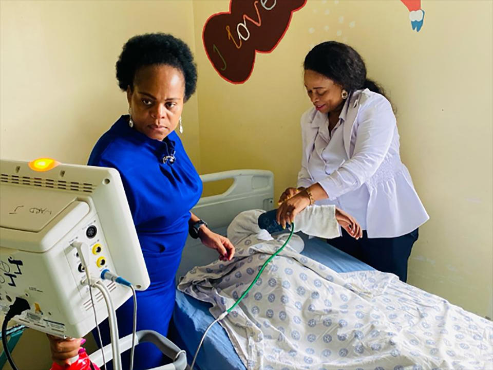 This photo supplied by the Government Health Department, Limpopo shows MEC for health, Dr Phophi Ramathuba, left, and a staff member at an undisclosed hospital, Friday, March 29, 2023, where they attend to the eight-year-old sole survivor of a bus crash that killed at least 45 people. Forensic investigators in South Africa are searching for the bodies of victims after a bus carrying pilgrims to an Easter gathering plunged off a bridge and caught fire. (South African Health Department via AP)