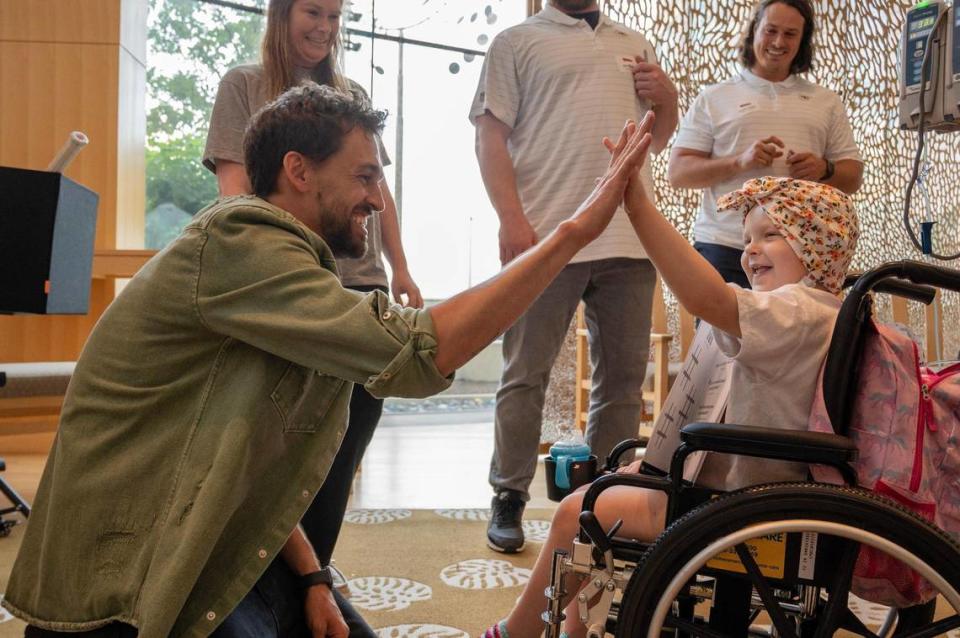 Blake Vogt, left, magician and Big Slick guest, high-fives Lexi Rentfro, 4, after performing a magic trick at Children’s Mercy Hospital Thursday.