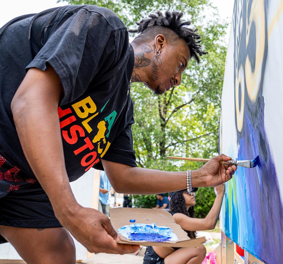 June Tate of Milwaukee creates a mural for the "I am Juneteenth" mural contest in the 52nd Juneteenth Jubilee Parade on June 19, 2023, in Milwaukee.