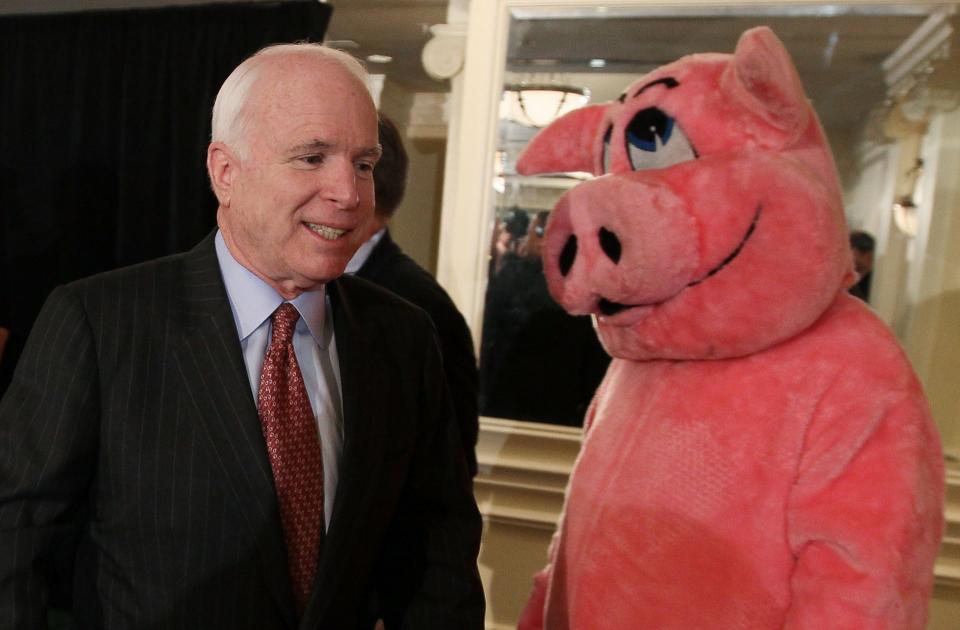 The late  Sen. John McCain and someone in a pig costume at a press conference on pork barrel spending on April 14, 2010, in Washington, DC.