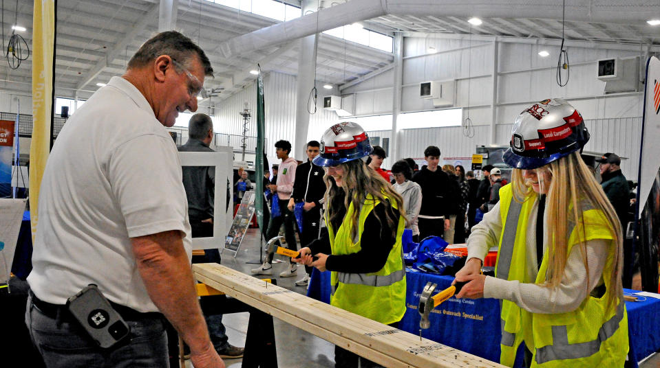 Carpenters Union representative Tom Boggs watches as Brooklyn Nelson and Ashley Bryant race each other pounding a nail into a 2x4 piece of wood.