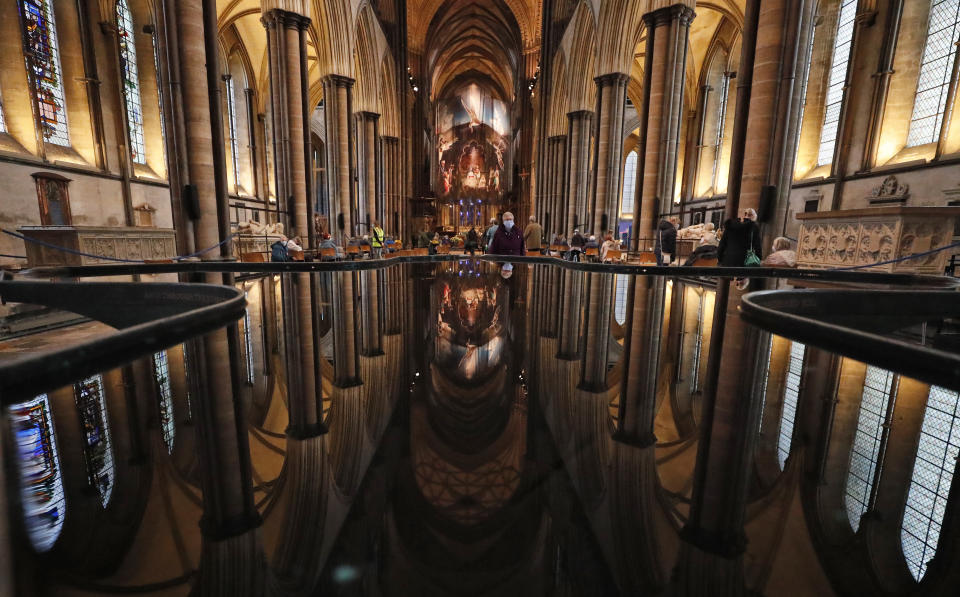 People are reflected in the 'Refection Pool' inside Salisbury Cathedral in Salisbury, England, Wednesday, Jan. 20, 2021, as they leave after receiving their Pfizer-BioNTech vaccination. Salisbury Cathedral opened its doors for the second time as a venue for the Sarum South Primary Care Network COVID-19 Local Vaccination Service. (AP Photo/Frank Augstein)