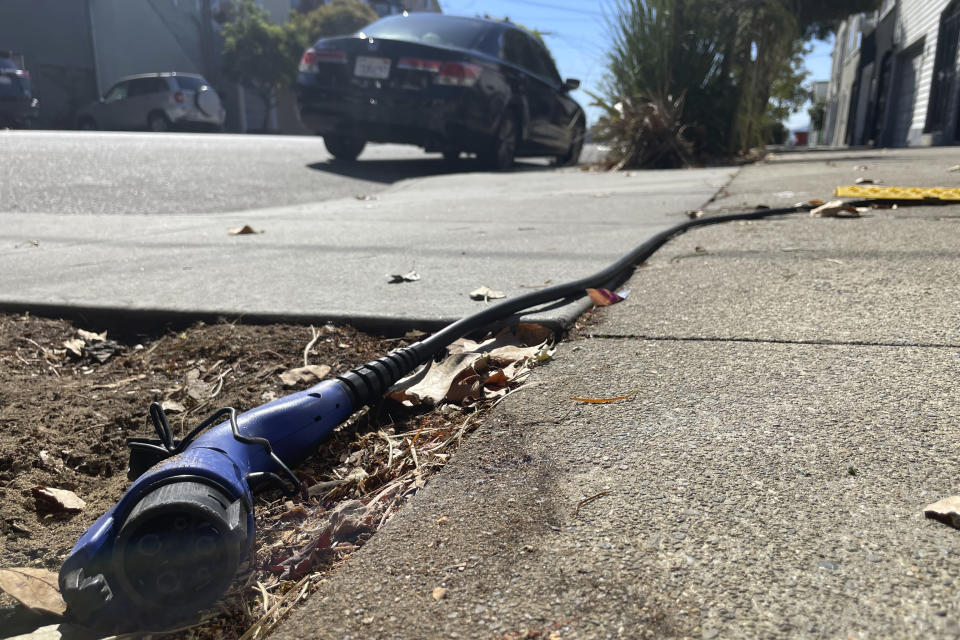 A charging cord for electric vehicles is seen strung across a public sidewalk in San Francisco on Sept. 23, 2022. The great transition to electric vehicles is underway for homeowners who can charge their cars in a private garage, but for millions of renters access to charging remains a significant barrier. Renters have resorted to stringing extension cords across public sidewalks and erecting private chargers in public rights-of-way as cities try to install more public charging to meet the demand. (AP Photo/Haven Daley)