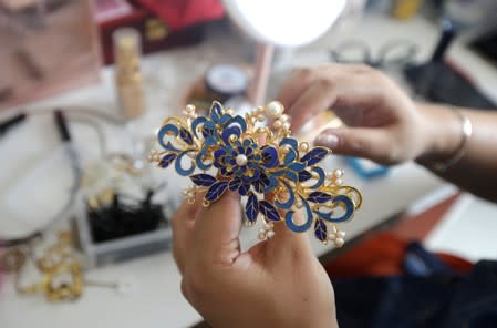 Li Doudou holds a hair ornament as she gets ready to attend a performance of the "guqin" traditional musical instrument, at her rental home in Hebei province, China