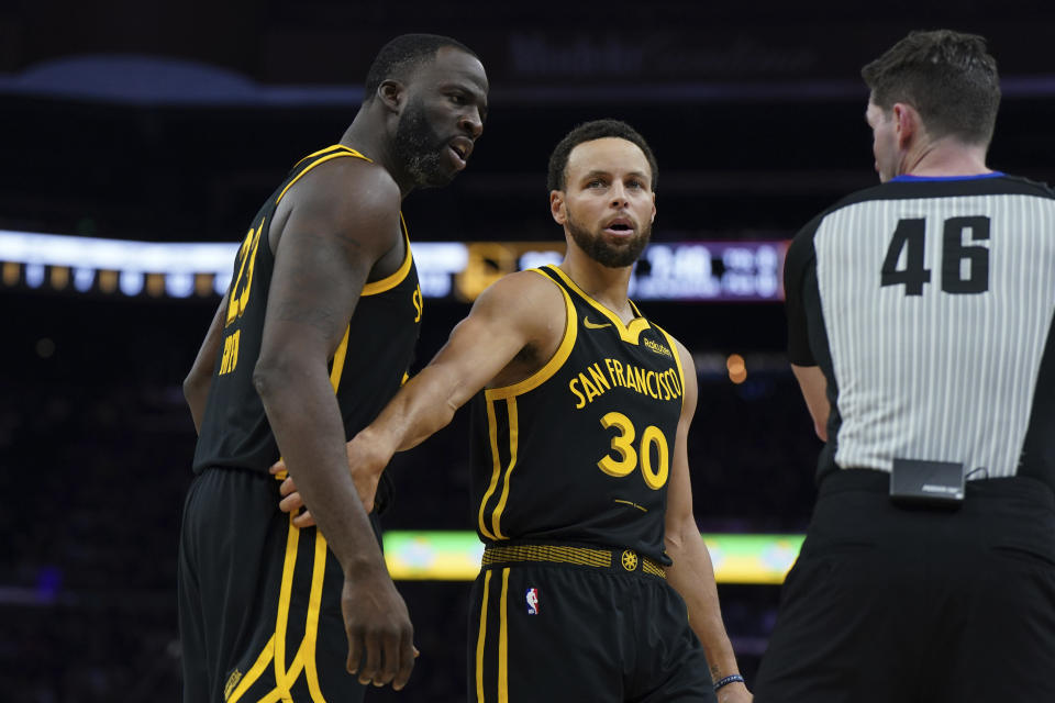 Golden State Warriors guard Stephen Curry (30) restrains teammate forward Draymond Green (23) following a call during the first half of an NBA basketball game against the Cleveland Cavaliers on Saturday, Nov. 11, 2023, in San Francisco. (AP Photo/Loren Elliott)