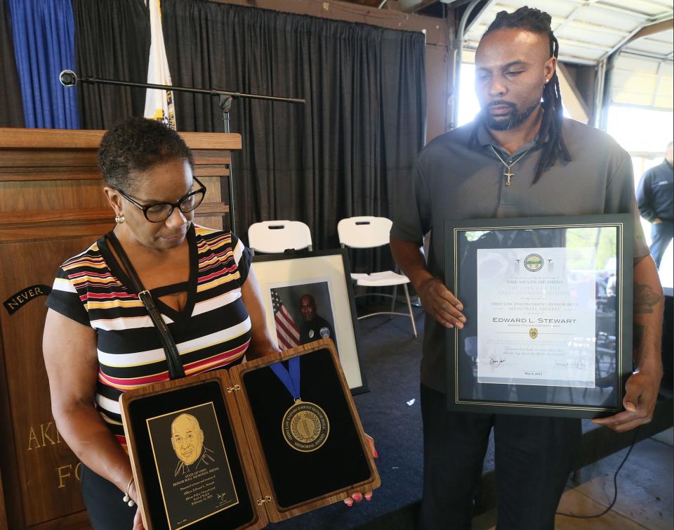 Lisa Stewart, the wife of late officer Edward Stewart, and their son, Jason Stewart, hold a medallion and a proclamation after the Akron polce memorial ceremony Wednesday.