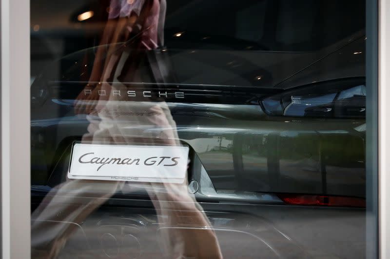 A woman walks past a Porsche 718 Cayman GTS sports car on display at its dealership in Seoul