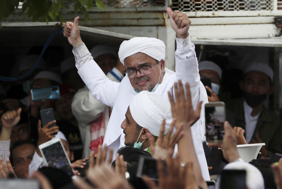 FILE - In this Tuesday, Nov. 10, 2020, file photo, Indonesian Islamic cleric and the leader of Islamic Defenders Front Rizieq Shihab, center, gestures to his followers as he arrives from Saudi Arabia in Jakarta, Indonesia. Shihab was sentenced to another four years in prison on Thursday, June 24, 2021, for concealing information about his coronavirus test result. (AP Photo/Achmad Ibrahim, File)