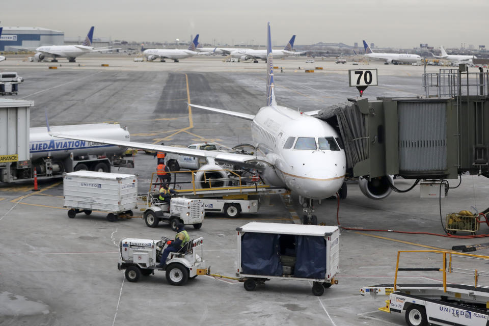 In this Jan. 23, 2019, photo a United Airlines jet is parked at a gate as luggage handlers pull carts near the terminal at Newark Liberty International Airport in Newark, N.J. United Airlines reports financial results on Tuesday, July 16. (AP Photo/Julio Cortez)