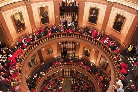 Labor union members and supporters hang a flag in the Capitol rotunda as they demonstrate in opposition to a proposed right-to-work measure inside the capitol building in Lansing, Michigan in this December 11, 2012, file photo. REUTERS/James Fassinger/Files