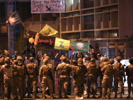 Supporters of Lebanese Shiite groups Hezbollah and Amal wave flags and chant in front of army soldiers in the capital Beirut