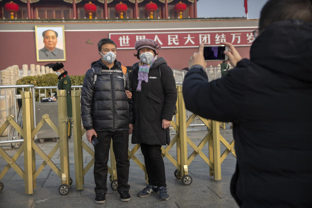 Tourists wear face masks as they pose for photos at Tiananmen Gate adjacent to Tiananmen Square in Beijing, Monday, Jan. 27, 2020. China on Monday expanded sweeping efforts to contain a viral disease by postponing the end of this week's Lunar New Year holiday to keep the public at home and avoid spreading infection as the death toll rose to 80. (AP Photo/Mark Schiefelbein)