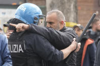 An Italian Police officers in riot gears talks to a Roma soccer fan as soccer supporters gather outside the stadium ahead of the Italian Serie A soccer match between Lazio and Roma at Rome's Olympic stadium, Sunday, March 19, 2023. (AP Photo/Gregorio Borgia)