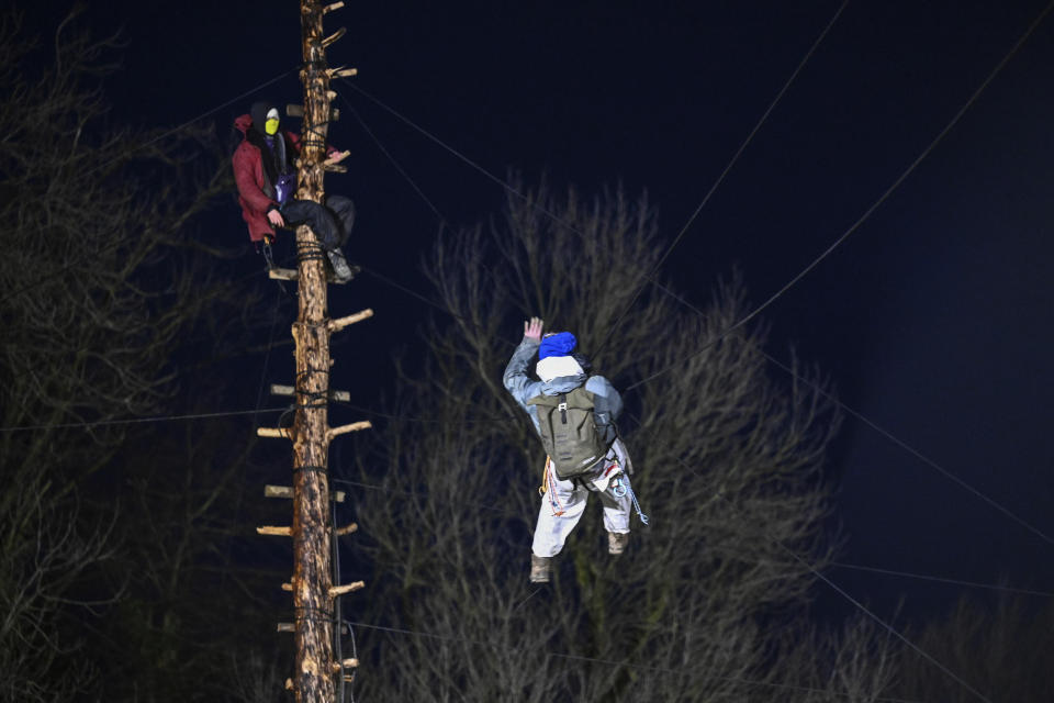 Activists climb wire ropes between trees during a protest near Erkelenz, Germany, Thursday, Jan. 12, 2023. Environmental activists have been locked in a standoff with police who started eviction operations on Wednesday around the hamlet of Luetzerath, west of Cologne, that is due to be bulldozed for the expansion of a nearby lignite mine. (Henning Kaiser/dpa via AP)