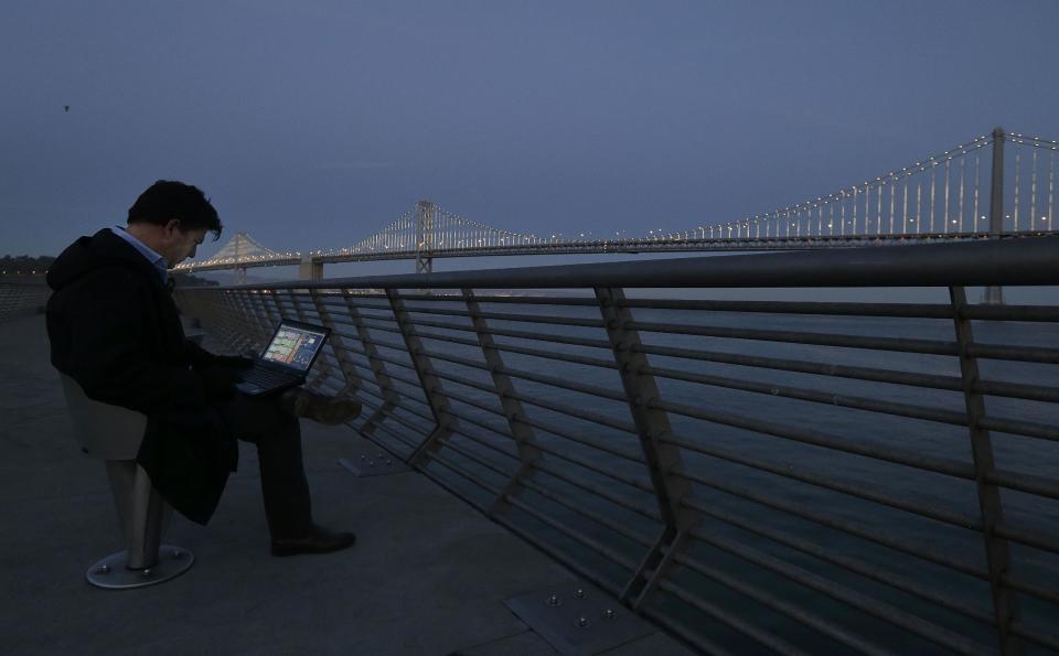 In this Wednesday, Feb. 20, 2013, photo, Artist Leo Villareal poses for photographs as he operates lights on the San Francisco-Oakland Bay Bridge on Pier 14 in San Francisco. The San Francisco-Oakland Bay Bridge has been turned into the latest, and by far the biggest, backdrop for New York artist Leo Villareal, who has individually programmed 25,000 white lights spaced a foot apart on 300 of the span’s vertical cables to create what is being billed as the world’s largest illuminated sculpture. (AP Photo/Jeff Chiu)