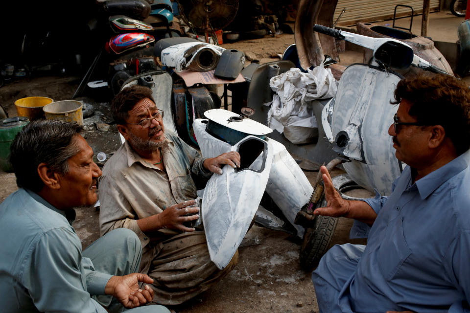 <p>Akram (C) applies coating on Vespa scooter parts, as he chats with owners of Vespa scooters Farrukh Shahbaz (L) and Matiur Rehman outside his workshop in Karachi, Pakistan Feb. 24, 2018. (Photo: Akhtar Soomro/Reuters) </p>