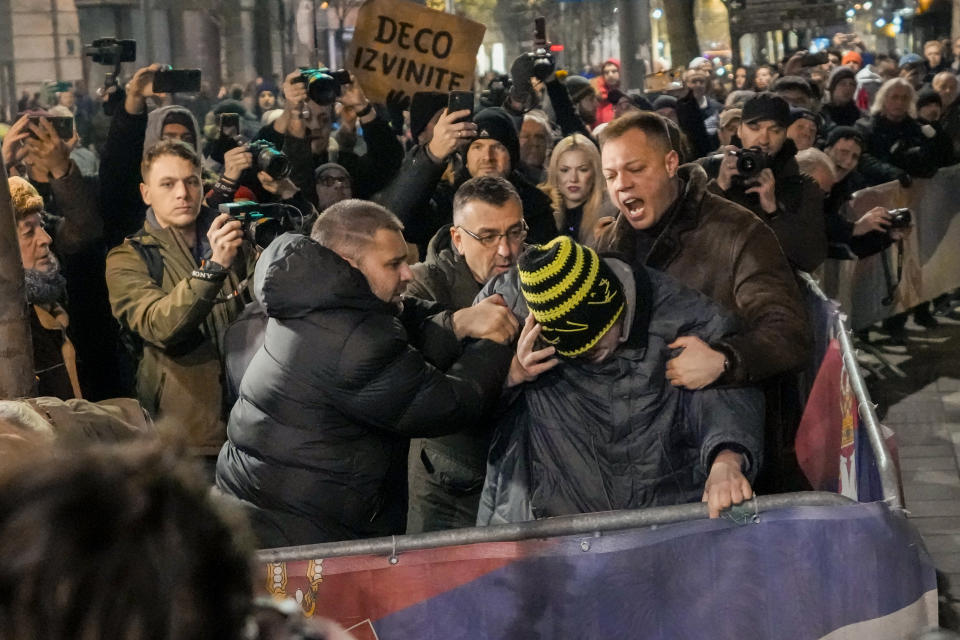 A Serbian opposition supporter is restrained by fellow protesters trying to avoid a violent escalation during a protest joined by several thousand people, outside the country's electoral commission in Belgrade, Serbia, Monday, Dec. 18, 2023. An early official vote count of Serbia's weekend election on Monday confirmed victory for the ruling populist party in a parliamentary vote in the Balkan country, but political tensions rose over reported irregularities in the capital, Belgrade. (AP Photo/Darko Vojinovic)