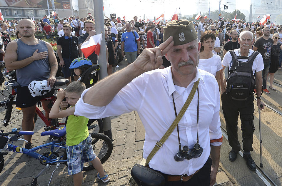 Warsaw residents stand with national flags and flares to observe a minute of silence for the fighters and victims of the 1944 Warsaw Rising against the Nazi German occupiers, on the 74th anniversary of the revolt, in downtown Warsaw, Poland, Wednesday, Aug. 1, 2018. (AP Photo/Czarek Sokolowski)