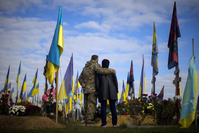 Los padres del militar ucraniano asesinado Ruslan Zhumaboev junto a su tumba en un cementerio durante el Día de los Defensores de Ucrania en Kharkiv, Ucrania, el 14 de octubre de 2022