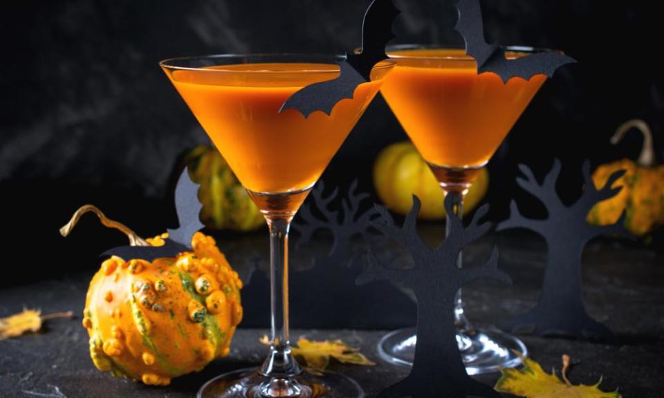 Orange martini cocktails with bats and decor for Halloween party